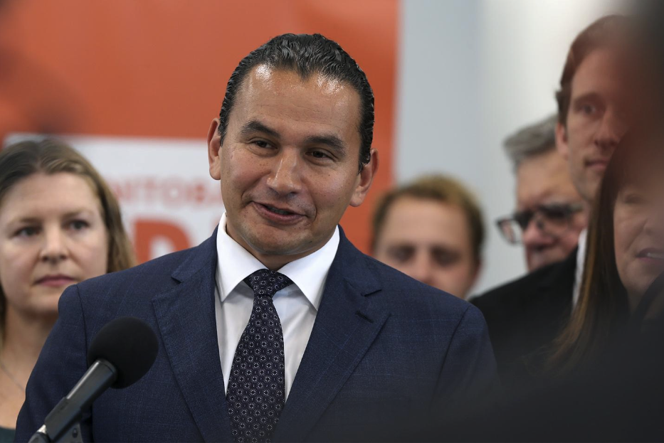 Wab Kinew stands at a podium and speaks to reporters shortly before becoming Manitoba’s 25th premier.